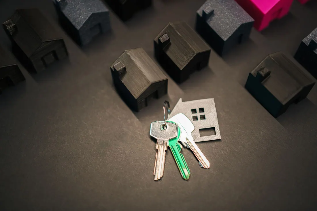 Llaves sobre un llavero con forma de casa junto a miniaturas de viviendas