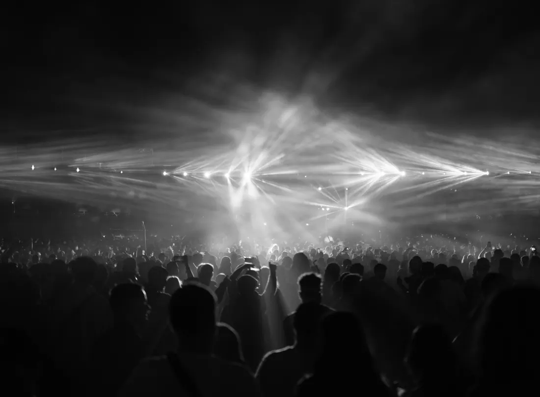 Multitud entre haces de luz durante un concierto nocturno