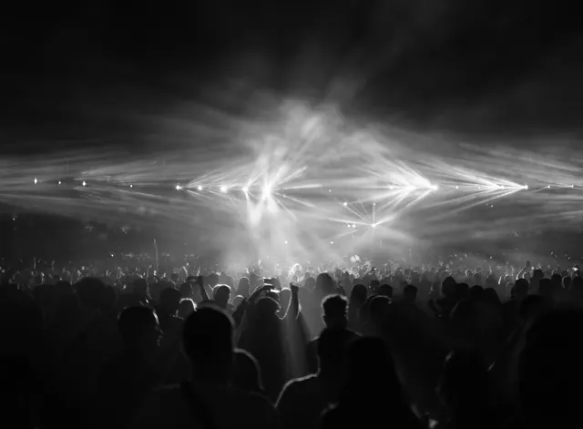 Multitud entre haces de luz durante un concierto nocturno