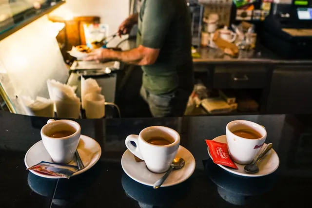 Tres tazas de café exprés sobre la barra de un bar