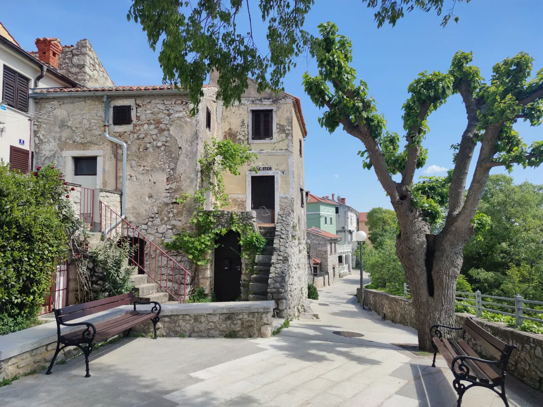 Calle empedrada de un pueblo con casas de piedra y bancos