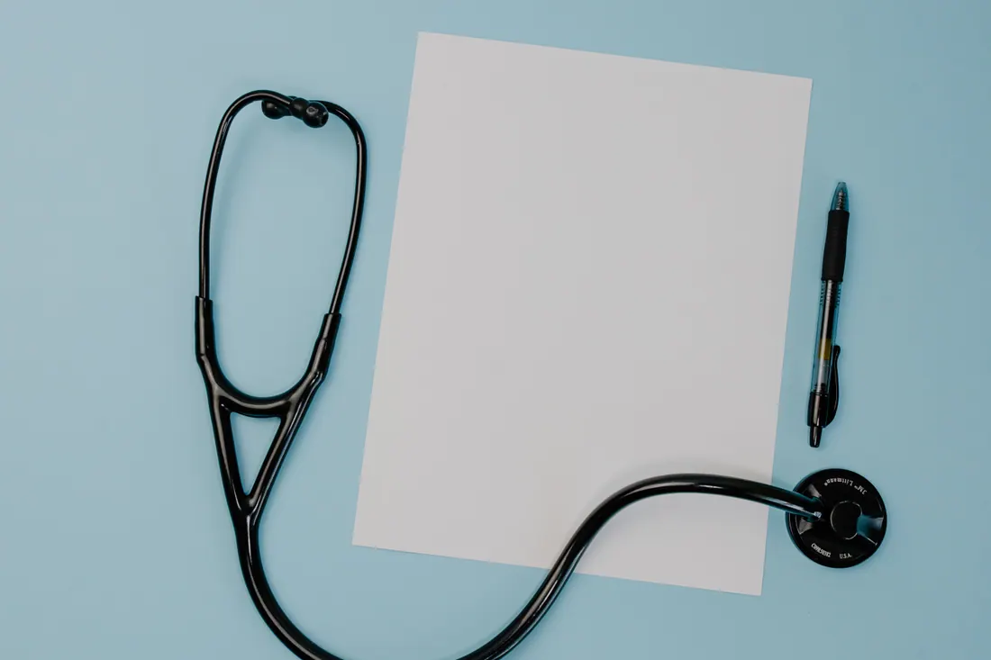 Un estetoscopio, un folio en blanco y un bolígrafo sobre una mesa