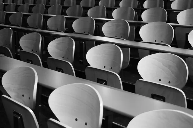 Filas de sillas de madera vacías en un aula o auditorio