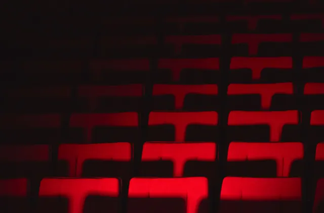 Butacas vacías de un auditorio o sala de cine iluminadas en rojo