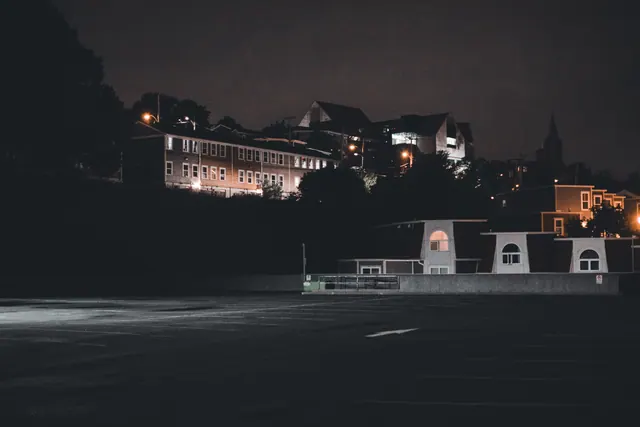 Vista nocturna de un aparcamiento vacío junto a edificios iluminados