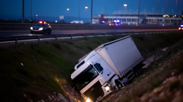 Camión volcado en una cuneta junto a una autopista al anochecer