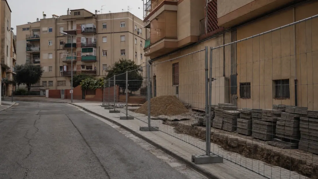 Calle urbana con edificios de viviendas y obra vallada en construcción