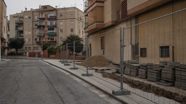Calle urbana con edificios de viviendas y obra vallada en construcción