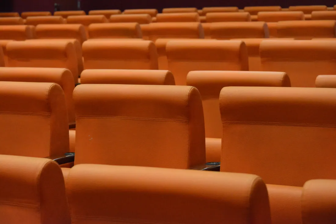 Filas de butacas vacías de color naranja en una sala