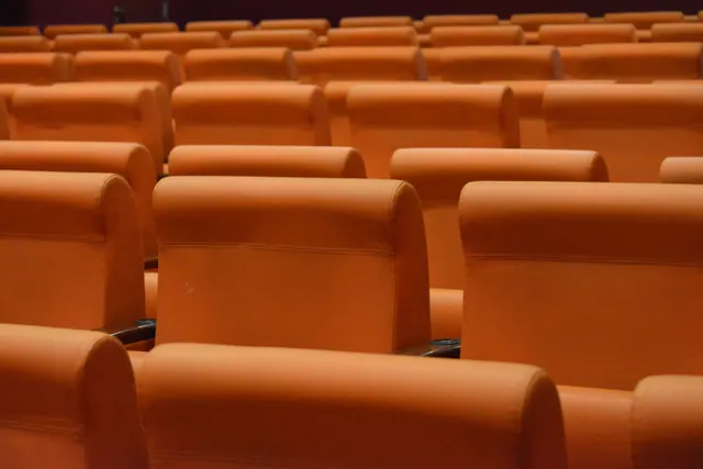 Filas de butacas vacías de color naranja en una sala