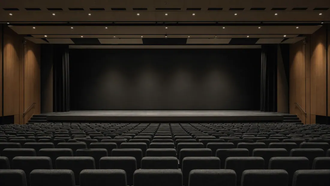 Butacas de cine vacías frente a un escenario oscuro