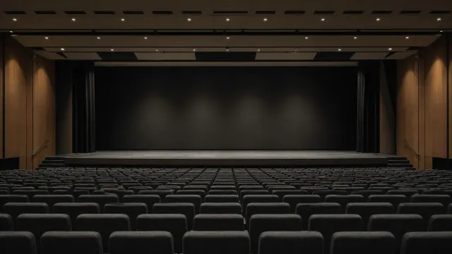 Butacas de cine vacías frente a un escenario oscuro