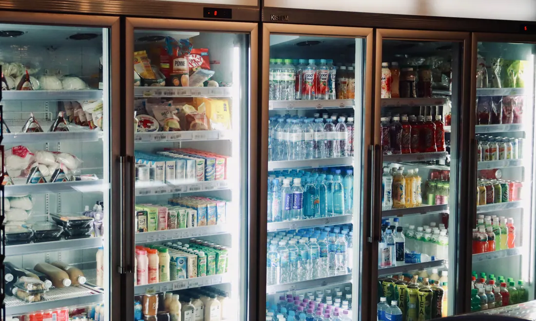 Varias neveras de supermercado llenas de bebidas y alimentos