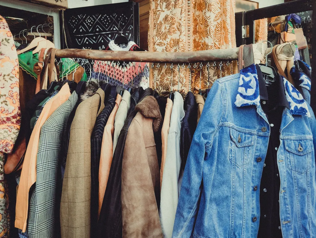 Perchero con varias prendas de ropa de segunda mano a la venta