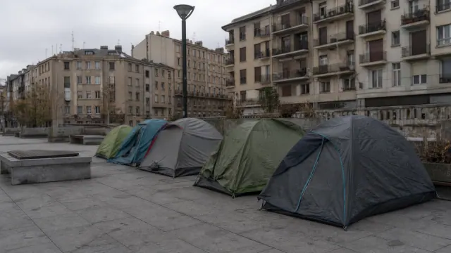 Tiendas de campaña instaladas en una plaza urbana frente a edificios residenciales