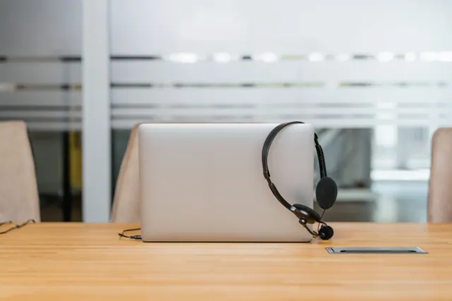 Un portátil cerrado con unos auriculares sobre una mesa de oficina