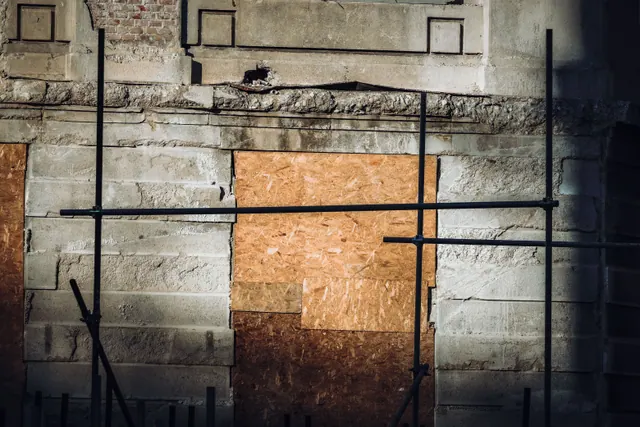 Fachada de un edificio en obras con andamios y tablones de madera