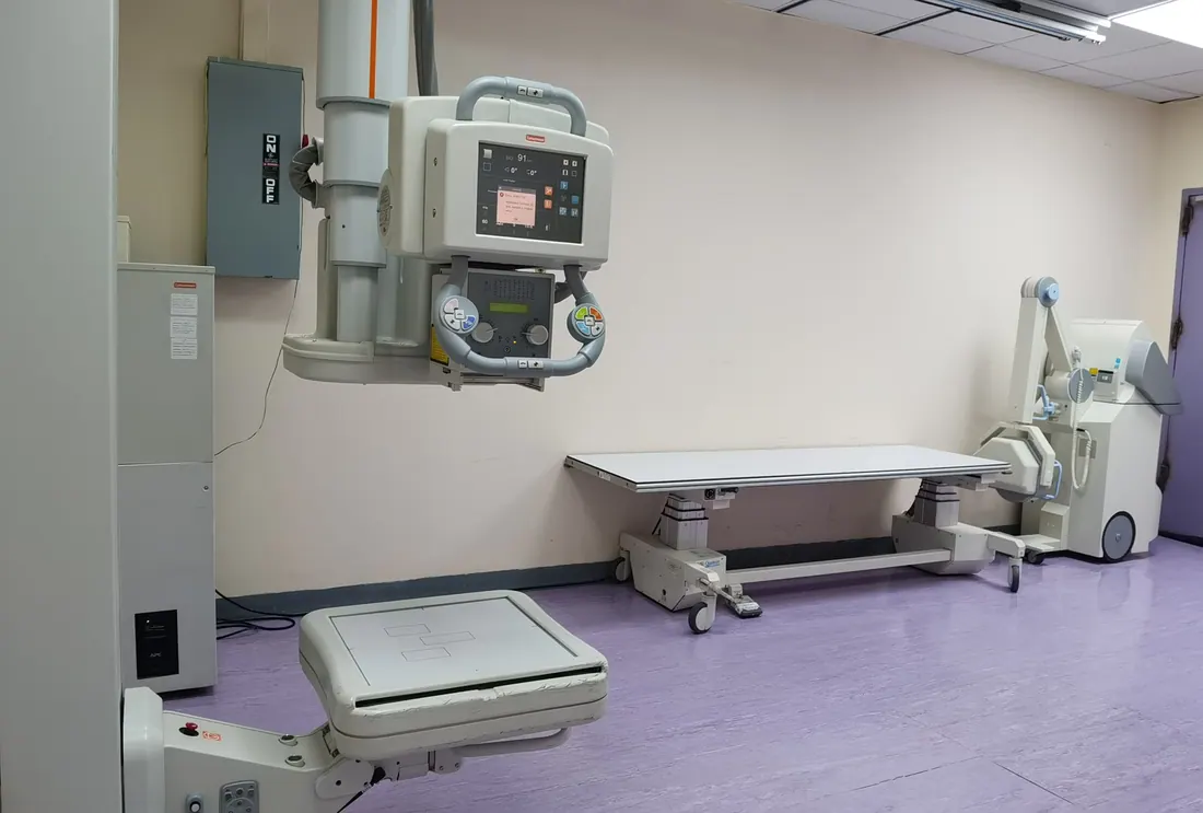 Sala de radiología con un equipo de rayos X y camilla