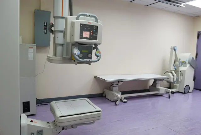Sala de radiología con un equipo de rayos X y camilla