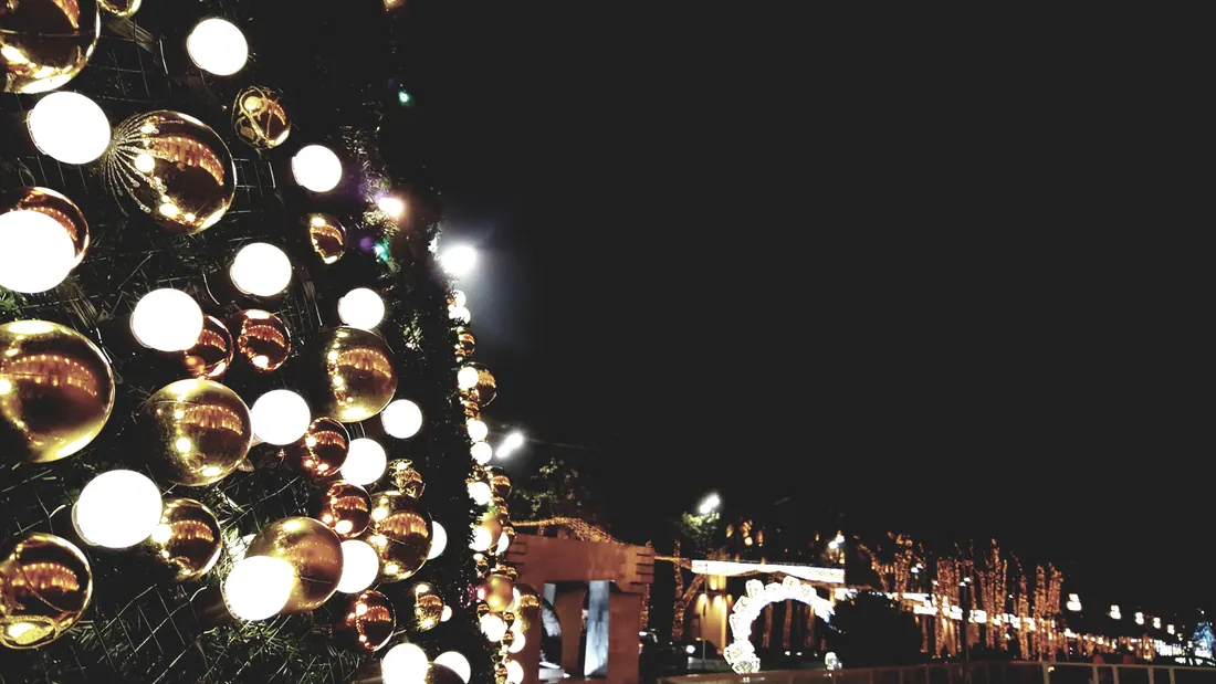 Árbol navideño decorado con bolas doradas iluminadas por la noche